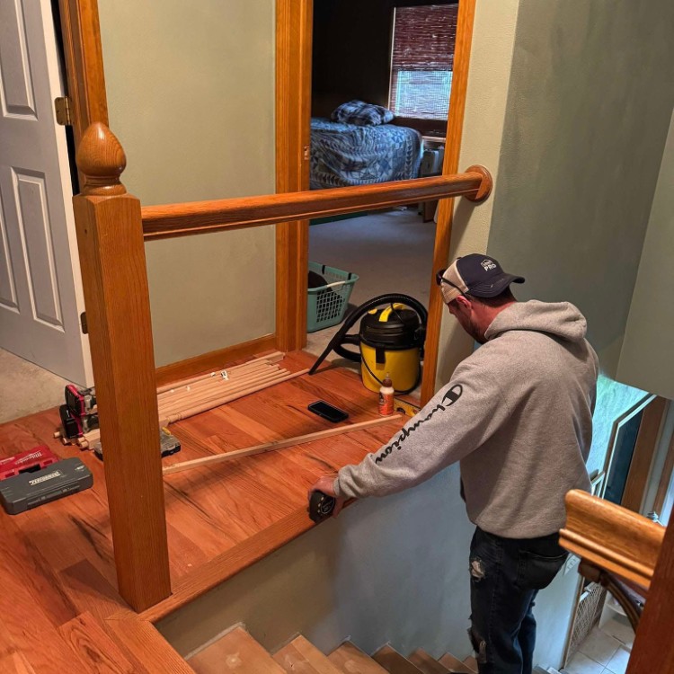 Man measuring wooden railing during custom home improvement project, showcasing craftsmanship and attention to detail in residential remodeling.