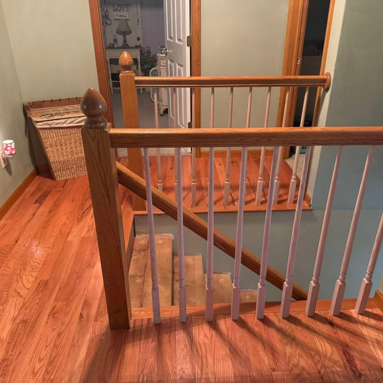 Interior view of a staircase with wooden railings and polished hardwood flooring, showcasing craftsmanship relevant to Forge Construction & Design's remodeling services.