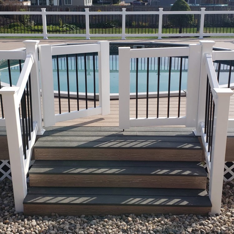 Custom deck with white railing and black balusters, leading to a pool area, showcasing Forge Construction & Design's craftsmanship in outdoor home improvement.